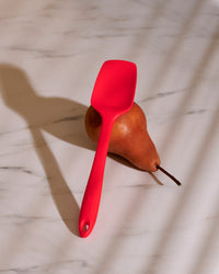 The GIR Red 3 Piece Mini Tool Set Mini Spoonula resting on a pear on a marble surface. 