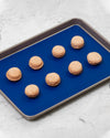 The Royal Blue 12 x 17 Baking mat on a baking tray with beige Macaroons on it. 