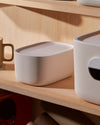 Close up of the Small Cream Storage bin with a plastic lid on a wooden surface.