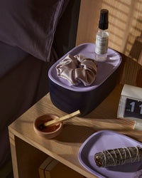  Small Navy Storage bin with a Lavender plastic lid on a side table.