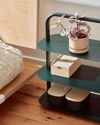 Side view of the Open Spaces Dark Green Entryway Rack on a wooden surface with items displayed on it.