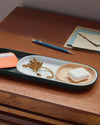Close up view of The Open Spaces Dark Green Nesting Tray with items on it on a wooden surface.
