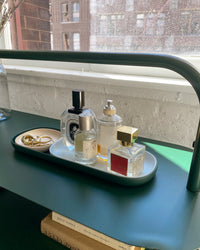 The Open Spaces Dark Green Nesting Tray with perfumes on it on a Dark Green Entryway rack. 