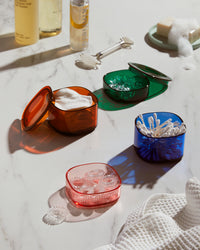The Multi - Color Storage gems with beauty products stored in it on a marble surface. 