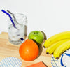 A straw from the Glass Straws in Cool Set in a glass on ice water next to some fruit. 