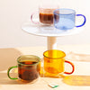 Four different colored Double Wall Mug displayed one filled with tea and one filled with coffee on a white background. 