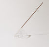 The Clear Glass Meso Incense Holder with an incense in it on a grayish background.