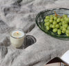 A 6 Oz Citronella Double wall  candle on a white background with a plate of green grapes on the upper right hand corner. 