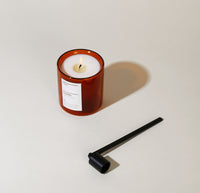 The Yield Candle Snuffer next to a Yield Candle on a cream background. 