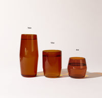 A 16 oz , 12 oz and 6 oz Amber Century Glasses lined up on a cream background. 