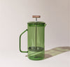 A Verde Glass French Press on a gray background.